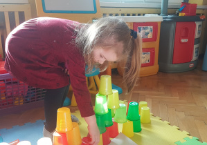 dzieci budują wieże z kolorowych kubeczków.